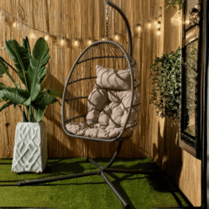Foldable Hanging Egg Chair in grey from OHS with beige cushion and metal stand styled in outdoor space