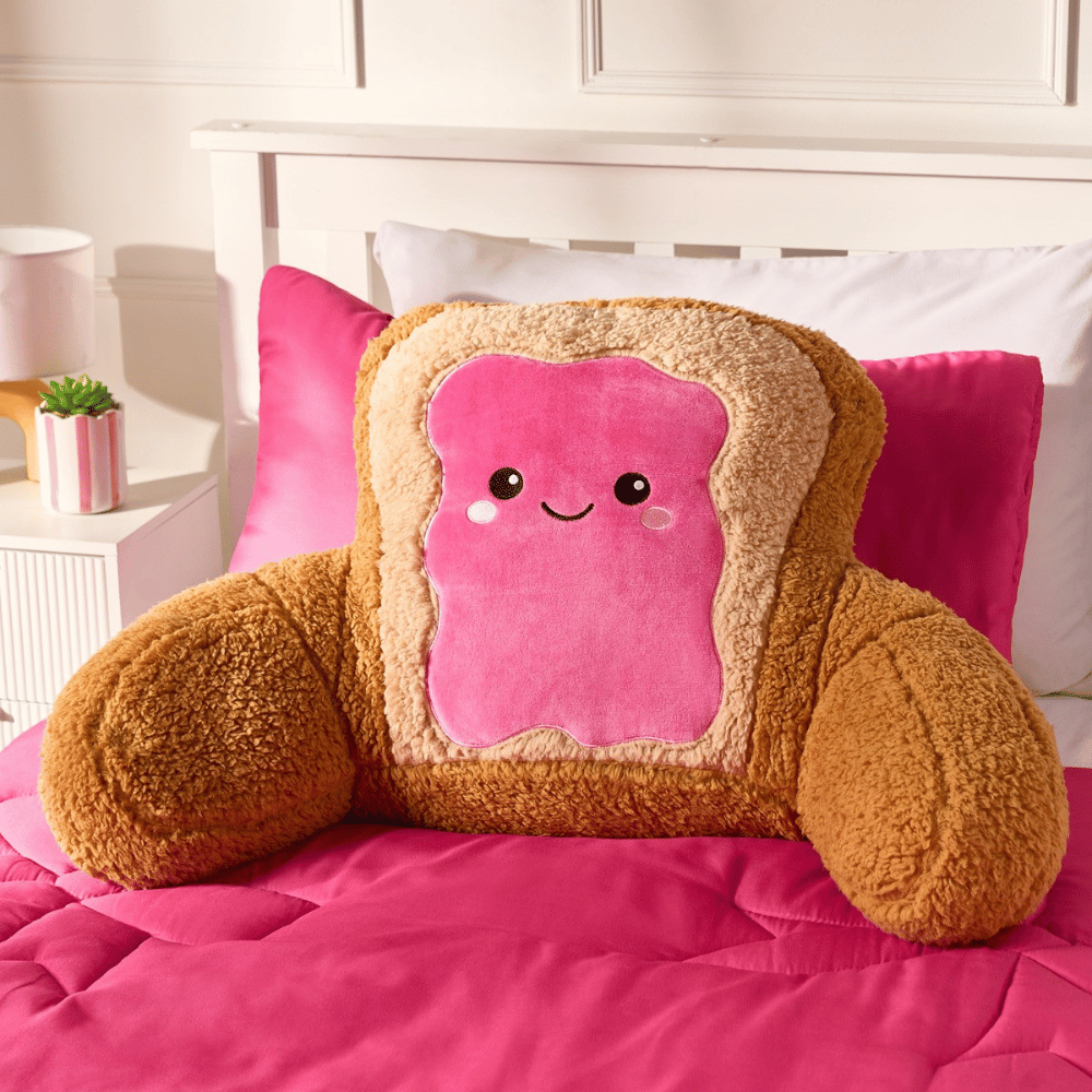 OHS Toast pink and brown character cuddle cushion on a bed